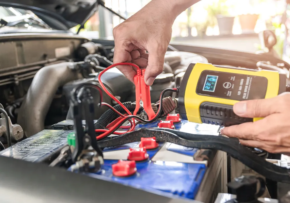 Mekanik mobil panggilan sedang melakukan jumper aki kendaraan.