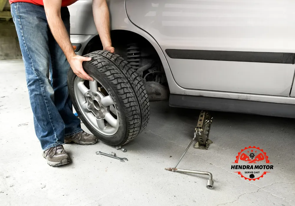 Teknisi bengkel panggilan sedang mengganti ban kendaraan.