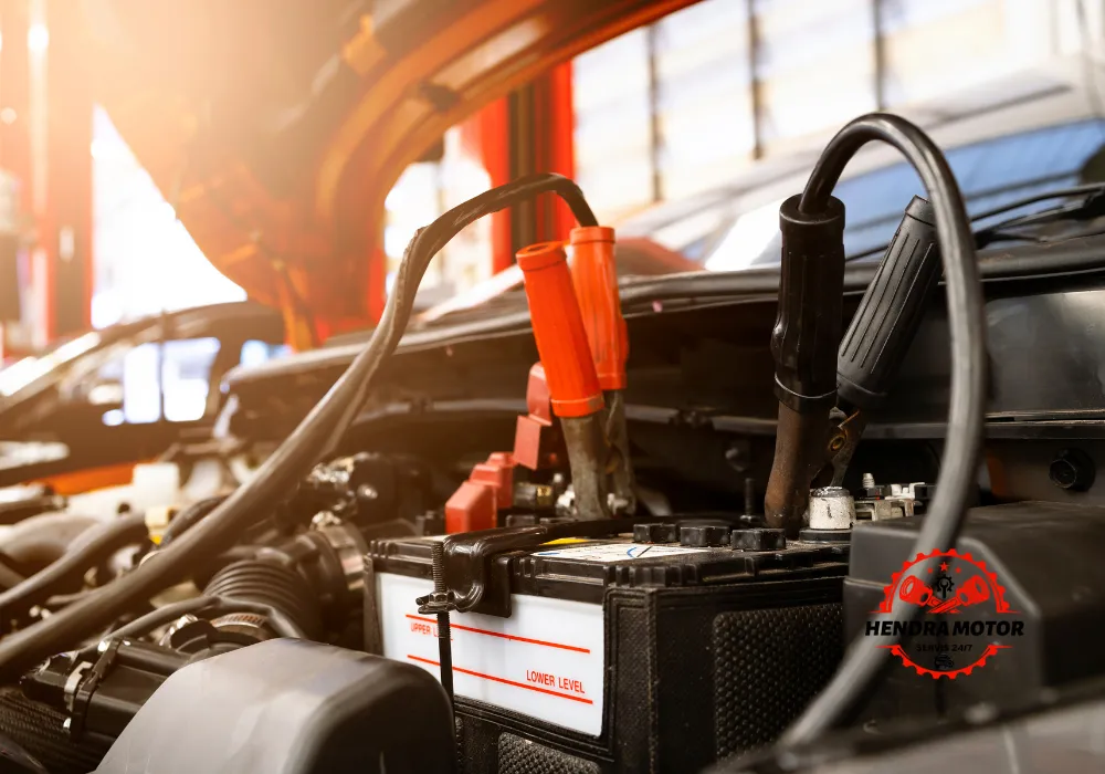 Montir mobil panggilan murah sedang melakukan jumper aki kendaraan.