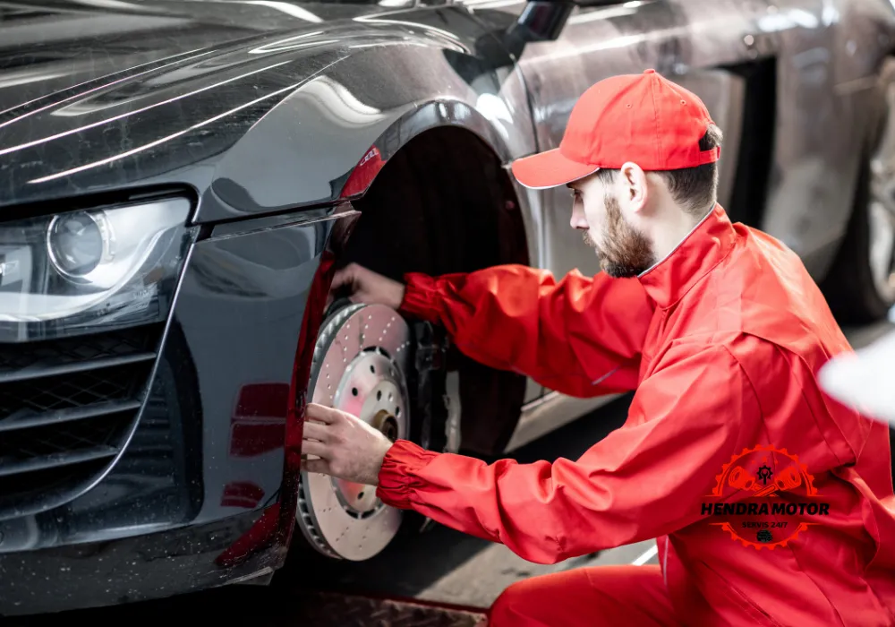 Montir mobil panggilan murah sedang mengganti ban kendaraan.