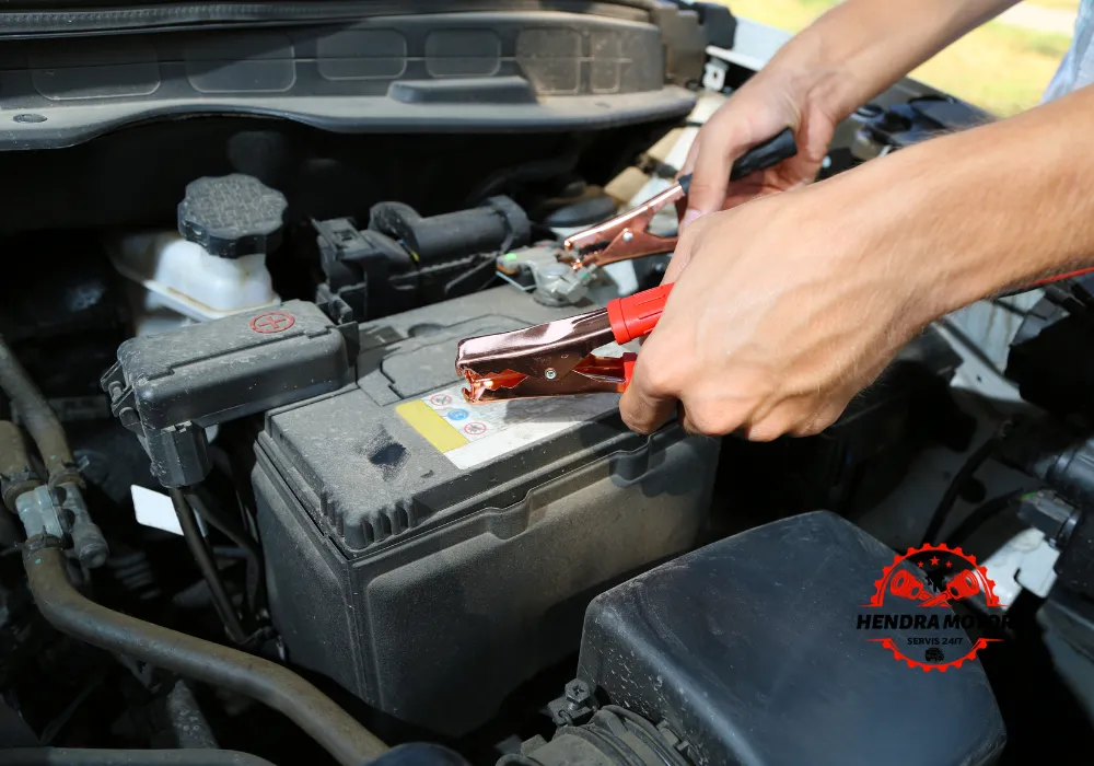 Montir mobil panggilan sedang melakukan jumper aki kendaraan.