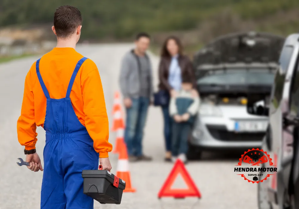 Montir panggilan sedang menangani mobil mogok di jalan.