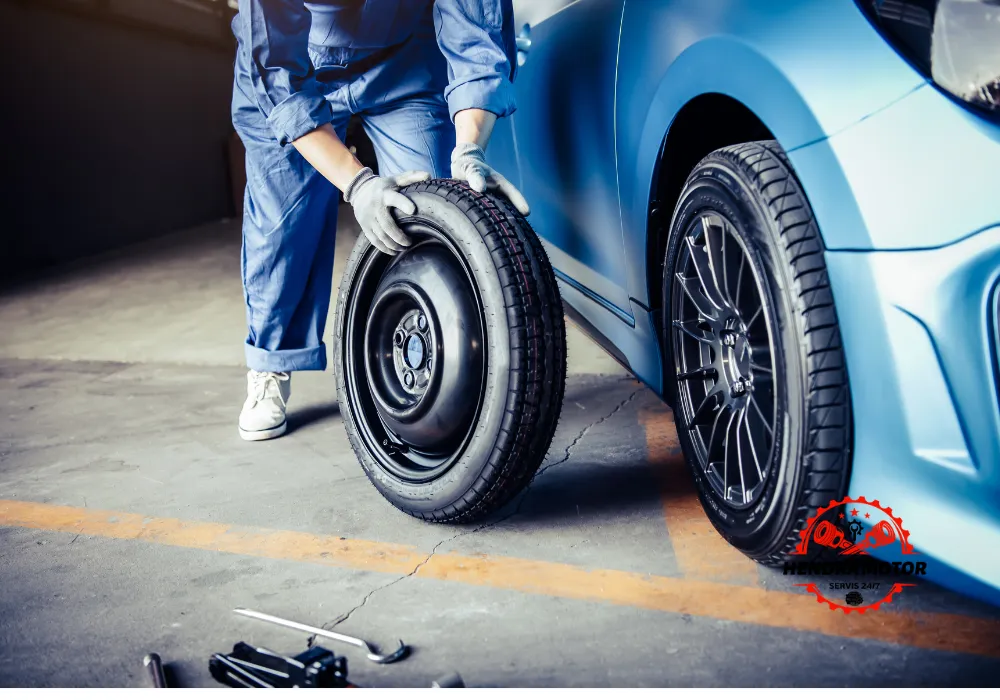 Servis mobil panggilan murah sedang mengganti ban kendaraan.